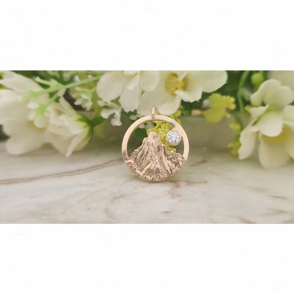 Gold pendant with a diamond on a marble surface with flowers in the background